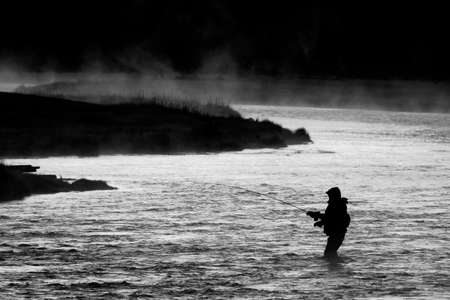 Silhouette of Fishing Flyfishing rod reel in river with golden sunlightの写真素材