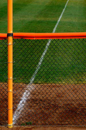 Outfield fence and green grass on baseball field diamond for competition and playing sportsの写真素材