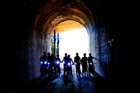 Group of people bikers biking through dark tunnel with headlights on Hiawatha Trailの写真素材