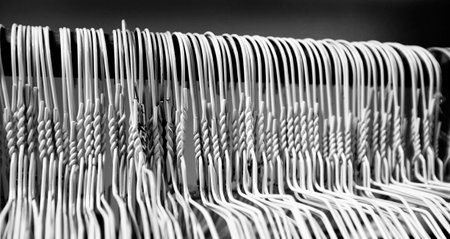 Many several metal wire hangers on pole for hanging clothing in closet storageの写真素材