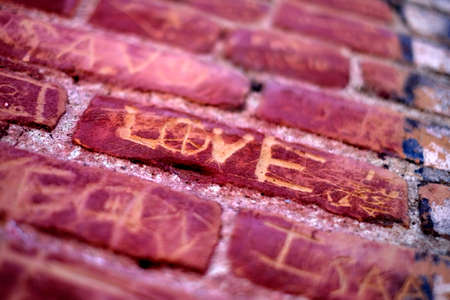 Love and symbol of affection scratched written on old brick wallの写真素材