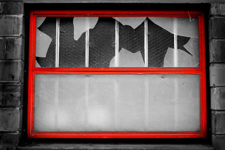 Window on building with broken glass shattered by vandalism destructionの写真素材