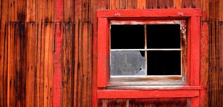 Detail of old weathered wooden barn wall with red paint windows and nailsの写真素材