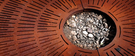 Rusty metal grate texture with rocks and soil in circle shapeの写真素材