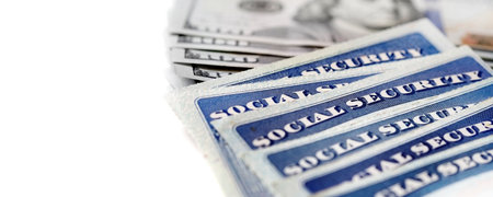 Closeup detail of several Social Security Cards representing finances and retirement with cash moneyの写真素材