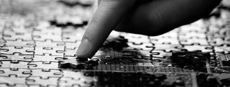 Hand with finger completing a jigsaw puzzle for fun and achievementの写真素材