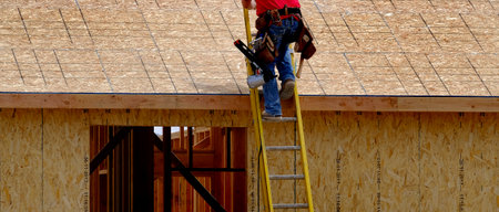Construction worker climbing up ladder work site on home being builtの写真素材
