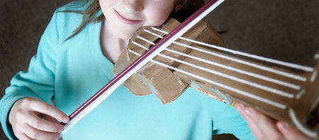 Young girl playing toy violin smiling happy and playfulの写真素材