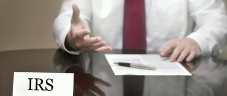 Businessman at desk with papers and card making hand gestures IRS Agentの写真素材