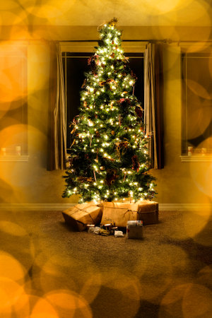 Christmas Tree in house living room with wrapped gifts at night windows out of focus golden lightsの写真素材