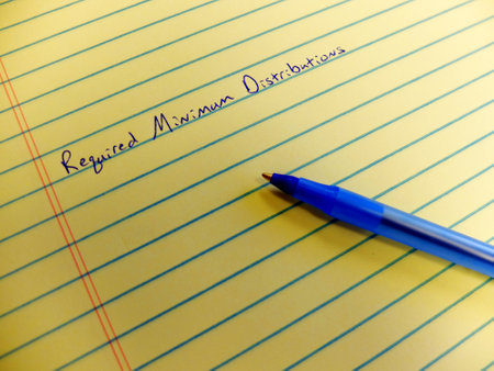 Required minimum distributions from retirement accounts written on yellow legal pad with blue pen notepad as reminderの写真素材