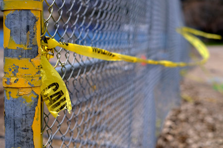 Yellow caution tape on fence for safety and security on propertyの写真素材