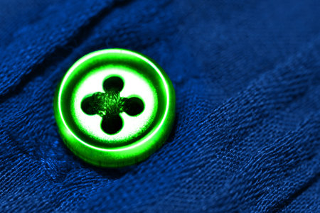 Detailed closeup macro of green button on blue shirt or cloth clothing with contrasting colors for fashionの写真素材