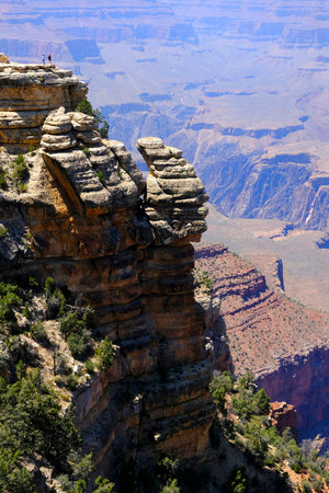 People or tourists standing on cliff taking selfies at the Grand Canyon in Arizona in the USA with amazing views of red rock cliffs and vistasの写真素材