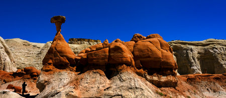 People in silhouette at Toadstool hoodoos in the Southwest with red sandstone and blue sky in wildernessの写真素材