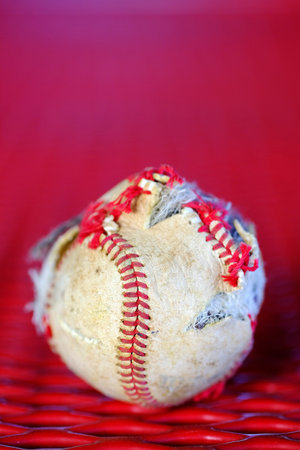 Closeup of old worn ragged baseball base ball with torn cover for sportの写真素材