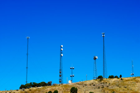 Several radio towers on top of hill for communication or telecommunication with blue skyの写真素材