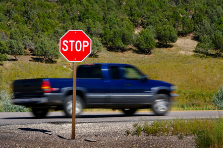 Bright red stop sign on road with blurry blurred moving car or truck speeding pastの写真素材