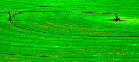 Irrigation pivot circle in lush green farm field with tracks on groundの写真素材