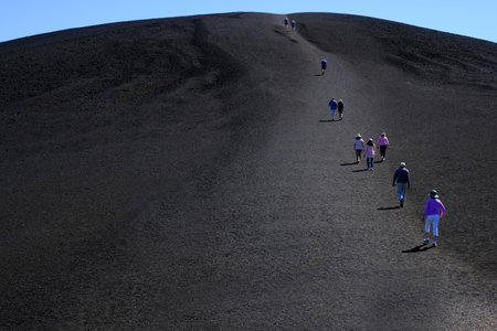 People tourists hiking on black lava cinder Inferno Cone at Craters of the Moon National Monumentの写真素材