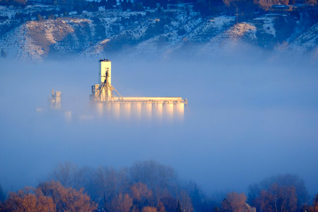 Foggy valley in city residential with granary building grainary in golden morning sunlight