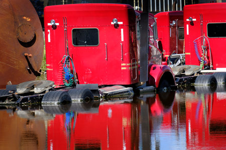 Flooded semi diesel big rig trucks that are red in flood waters