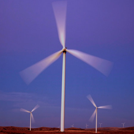 Windmill wind turbines spinning fast in wind at sunset or sunrise