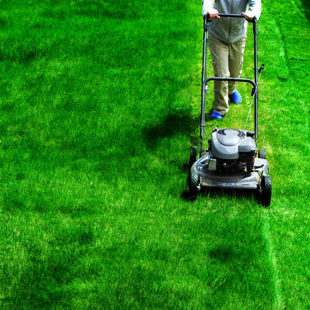 Young Girl Mowing green grass lawn with push mower landscaingの写真素材