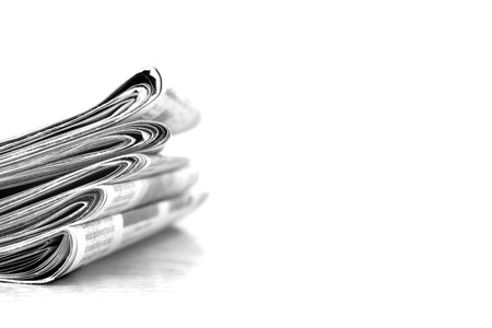 Piled up newspaper isolated on white background with latest breaking news communication in writingの写真素材