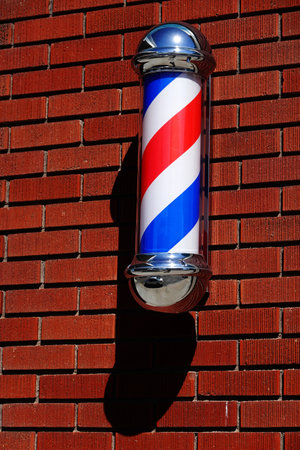 Detail of barber pole or sign on brick wall advertising haircuts shave and grooming shop for businessの写真素材