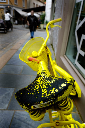 Detail of a worn old bike or bicycle parked on a sidewalk in town or city with people walkingの写真素材