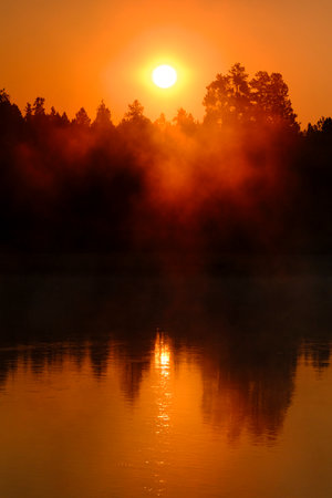 Detail of sunrise sun rising over river lake or pond with golden mist or fog risingの写真素材