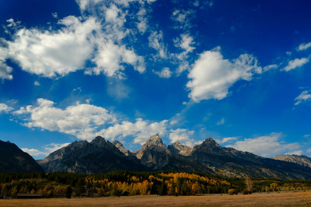 Detail of Grand Teton mountains Tetons mountain range in Wyoming in Autumn fall landscape with blue sky and dramatic cloudsの写真素材