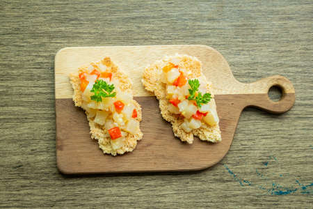 wooden plank with piece of cassava with carrot potato salad, top view