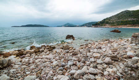 red orange sedimentary rocks on adriatic sea, budva riviera montenegro turquoise water beach and pebblesの写真素材