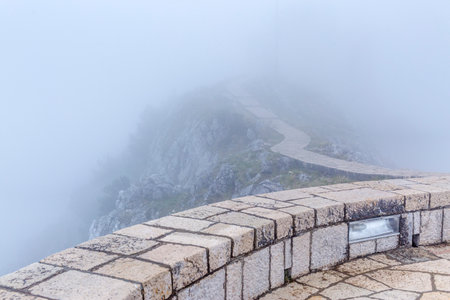 steep cloudy and misty mountains with stone footpath and platformの写真素材