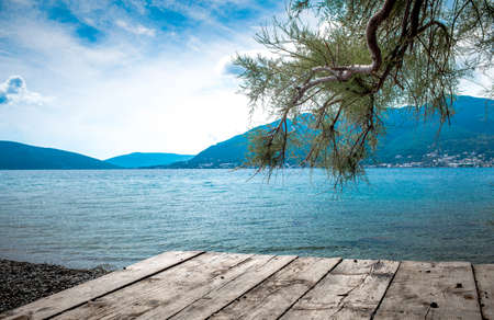 kotor bay beach with wooden platform and tree on the foreground and hills in the backgroundの写真素材