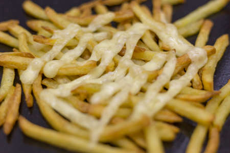 Close up of french fries with mayonnaise on a black plate