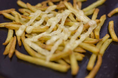 Fried potatoes with mayonnaise in a frying pan. Close-up.