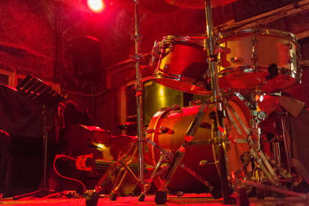 Drum set on stage in the night club. Red lighting.の写真素材