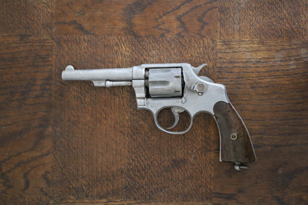 Revolver gun on a wooden background. Top view, copy space.