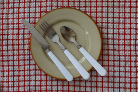 Plate with cutlery on a tablecloth, top viewの写真素材
