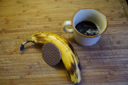 Cup of black coffee and a banana on a wooden table.の写真素材