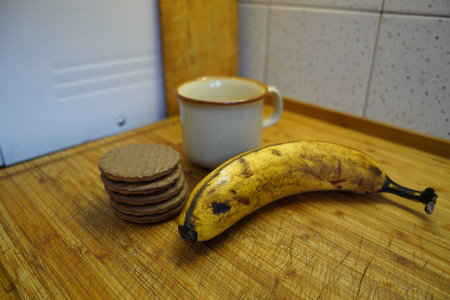 Banana and a cup of coffee on a wooden table in the kitchenの写真素材