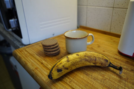 Cup of coffee and banana on a wooden table in the kitchenの写真素材