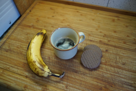Cup of coffee with chocolate chip cookies and banana on wooden tableの写真素材
