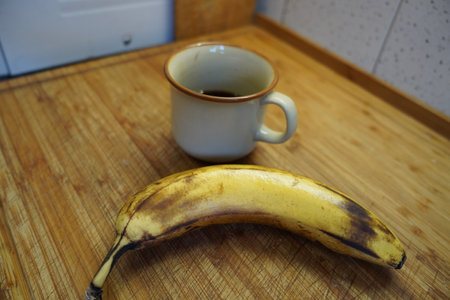 Cup of coffee and a banana on a wooden table in the kitchenの写真素材