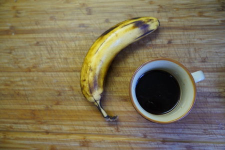 Cup of coffee and banana on wooden table. Top view.の写真素材