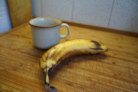 Banana and cup of coffee on a wooden table. Selective focus.の写真素材