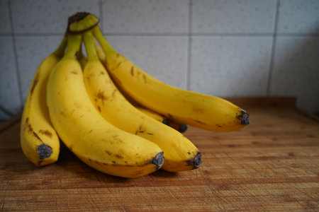 Bunch of bananas on a wooden table in a kitchen. Selective focus.の写真素材